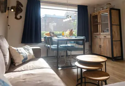 a living room with a table and chairs and a window at Gestrand in Egmond aan Zee