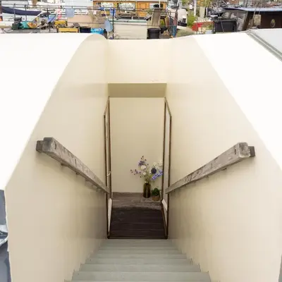 a staircase leading to a building with a vase of flowers at Boat suite - A Unique Houseboat Stay in Amsterdam in Amsterdam