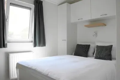 a bedroom with a white bed and a window at Chalet 4, Recreatie aan de Vecht in Weesp