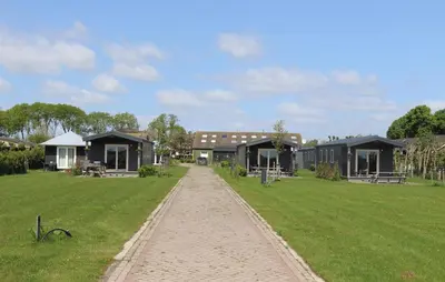a row of cottages in a field with a dirt road at Chalet 4, Recreatie aan de Vecht in Weesp