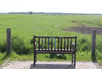 a bench sitting in a field with a fence at Chalet 4, Recreatie aan de Vecht in Weesp