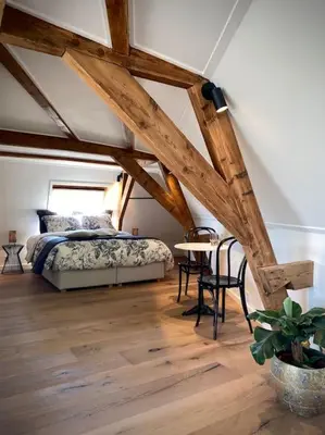 a bedroom with a bed and a table in a room at Cosy Penthouse with Rooftop Canalhouse-Majestic in Utrecht
