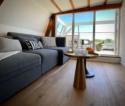 a living room with a blue couch and a table at Cosy Penthouse with Rooftop Canalhouse-Majestic in Utrecht