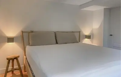 a bedroom with a white bed with two pillows and a stool at Beautiful Home In Loosdrecht With Wifi in Loosdrecht