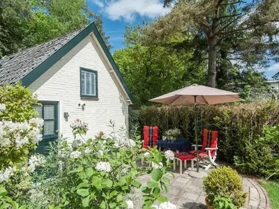 a garden with a table and chairs and an umbrella at Kleine Nachtegaal in Schoorl