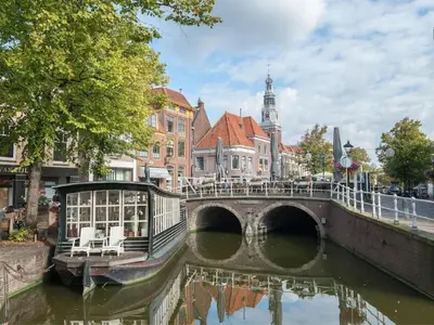 a boat on a river in a city with a bridge at Kleine Nachtegaal in Schoorl