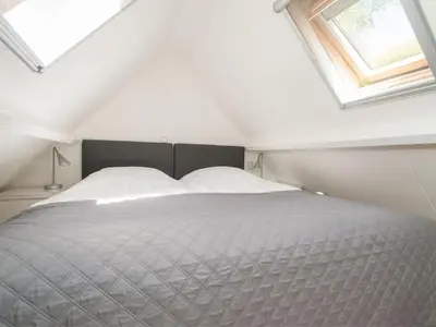 a bedroom with a large bed with a window at Kleine Nachtegaal in Schoorl