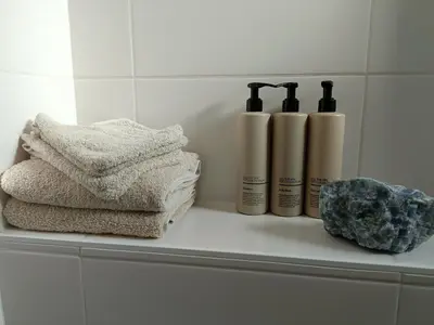 a shelf with three towels and a group of bottles at Cottage at Sea in Noordwijk aan Zee