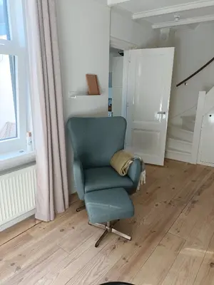 a green chair sitting in a room with a window at Cottage at Sea in Noordwijk aan Zee