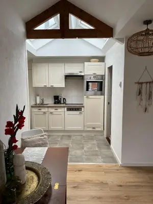 a kitchen with white cabinets and a table in a room at ZilverMoon in Egmond aan Zee