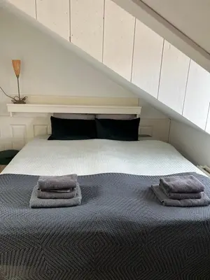 a bedroom with a bed with two towels on it at ZilverMoon in Egmond aan Zee