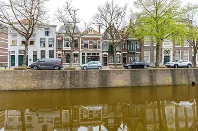a group of cars parked next to a body of water at Historisch grachtenpand in centrum Gouda in Gouda