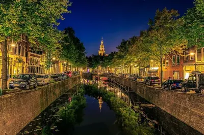 a canal in a city at night with cars parked at Historisch grachtenpand in centrum Gouda in Gouda