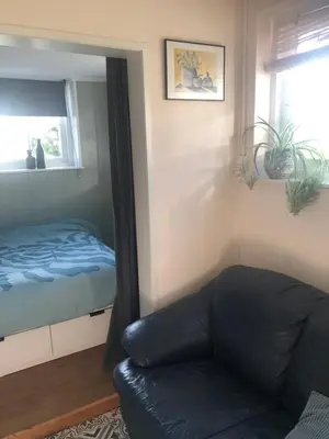 a living room with a couch and a bed and a mirror at Appartement in schuur in Twisk