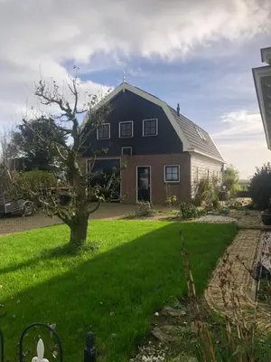 a large black house with a tree in the yard at Appartement in schuur in Twisk