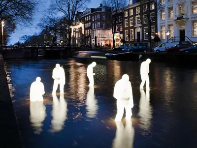 a group of people standing in the water at night at Heerlijke Houseboat 