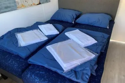 two beds with blue comforters and towels on them at Heerlijke Houseboat 