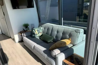 a gray couch with pillows sitting in a living room at Heerlijke Houseboat 