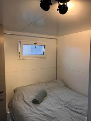 a bed in a small room with a window at Houseboat Oslo perfect voor bezoek Amsterdam in Monnickendam