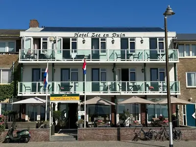 a building with tables and umbrellas in front of it at Hotel Zee en Duin in Katwijk