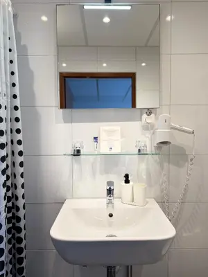 a white bathroom with a sink and a mirror at Hotel Zee en Duin in Katwijk