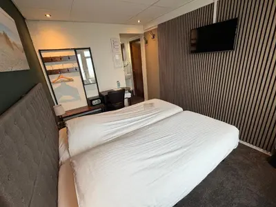 a hotel room with a bed and a television at Hotel Zee en Duin in Katwijk