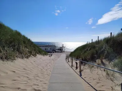 a path leading to a sandy beach next to the ocean at JulianaDuin in Bergen aan Zee
