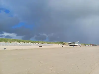 a sandy beach with a building in the background at JulianaDuin in Bergen aan Zee