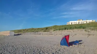 a kite sitting on a sandy beach with a building at JulianaDuin in Bergen aan Zee