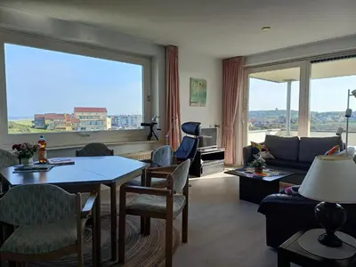 a living room with a couch and a table with chairs at JulianaDuin in Bergen aan Zee