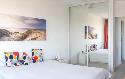 a white bedroom with a large white bed with pillows at JulianaDuin in Bergen aan Zee