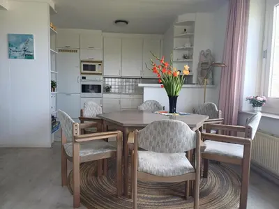 a kitchen with a wooden table with chairs and a vase of flowers at JulianaDuin in Bergen aan Zee