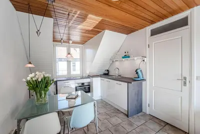 a kitchen with a table and some white cabinets at Rozenobel apartment in Zandvoort