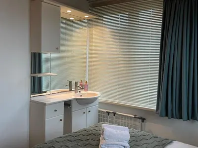 a bathroom with a sink and a window with blinds at Rozenobel apartment in Zandvoort