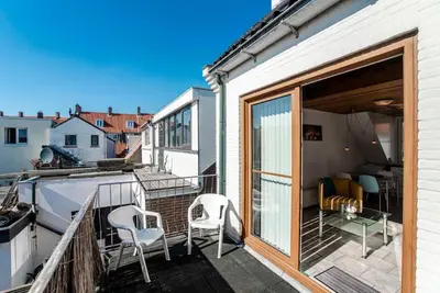 a balcony with two chairs and a sliding glass door at Rozenobel apartment in Zandvoort