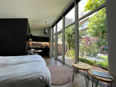 a bedroom with a large bed and large windows at Amsterdam Beach House in Zandvoort