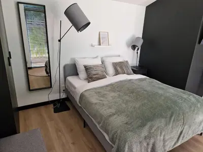 a bedroom with a bed and a lamp and a window at Amsterdam Beach House in Zandvoort
