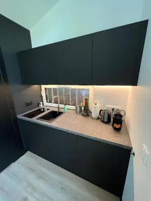 a kitchen counter with black cabinets and a sink at Amsterdam Beach House in Zandvoort