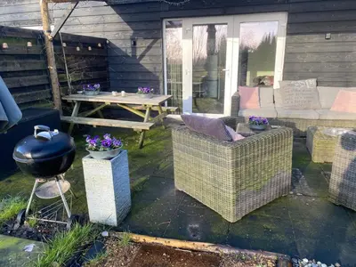 a patio with a grill and wicker chairs and a table at Guesthouse ML in Hillegom