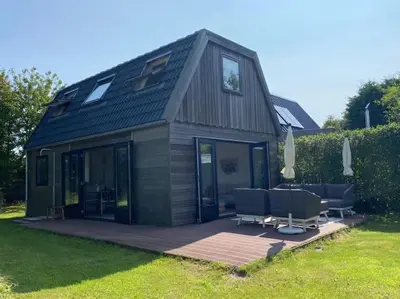 a small house with a deck and some chairs at Duinhuis Zout Hout in Egmond-Binnen