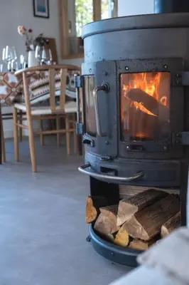 a stove with logs in a room with a table at Duinhuis Zout Hout in Egmond-Binnen
