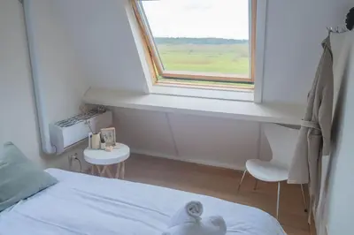 a bedroom with a bed and a window and two chairs at Duinhuis Zout Hout in Egmond-Binnen