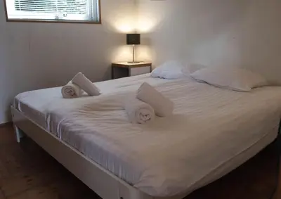 a large white bed with white sheets and pillows at Vakantiewoning MV8 in Egmond-Binnen