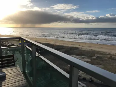 a balcony with a view of the beach and the ocean at Berrie's Sea View in Zandvoort