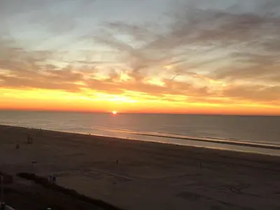 a sunset at the beach with people walking on the beach at Berrie's Sea View in Zandvoort