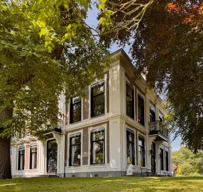 a large white house with large windows at Villa Abbekerk - Bed & Breakfast in Abbekerk