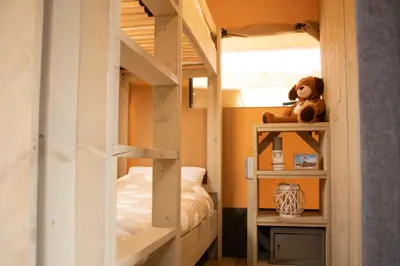 a bedroom with bunk beds with a teddy bear on a shelf at Safari Lodges in Nieuwe Wetering