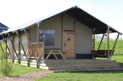 a small house with a porch and stairs in a field at Safari Lodges in Nieuwe Wetering