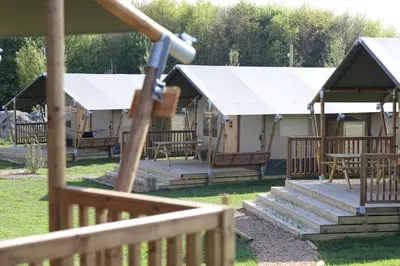 a group of lodges with benches and white roofs at Safari Lodges in Nieuwe Wetering