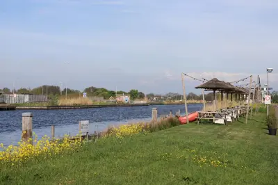 a dock with tables and a boat on the water at Safari Lodges in Nieuwe Wetering